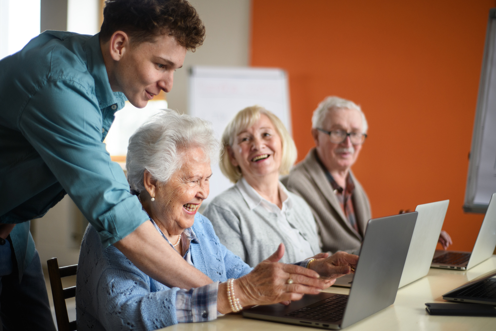 Groupe de seniors avec un jeune instructeur apprenant ensemble dans un cours d'informatique